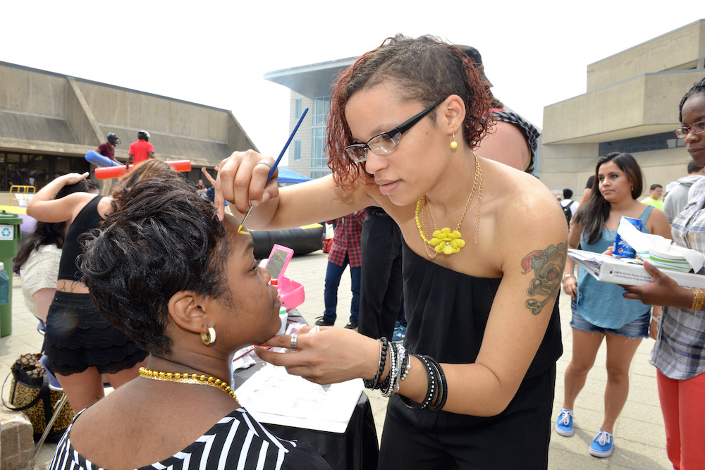 One female student painting another's face during an HCC event
